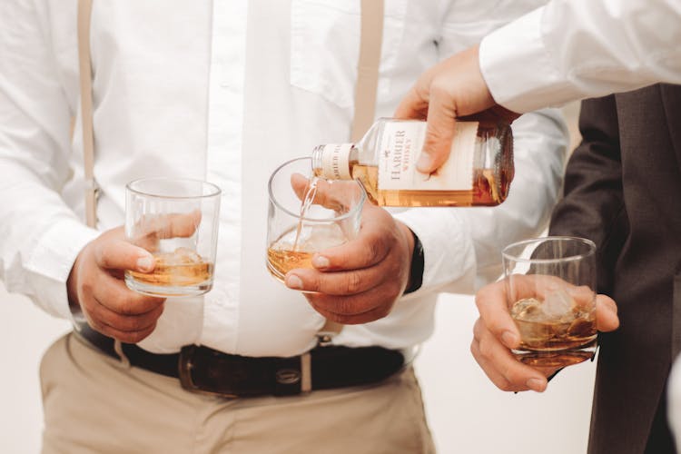 Hands Of Man Pouring Whisky Into Glass