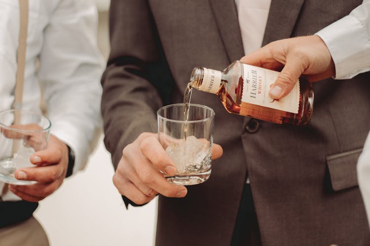 Close-up Of Man Pouring Whisky Into Glass