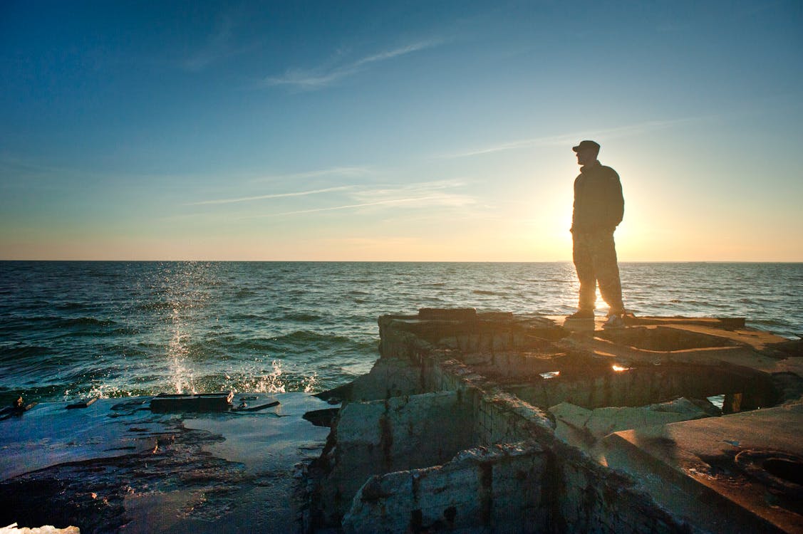 Free Silhouette Photo of Man Standing Near the Edge of Concrete Pavement Stock Photo