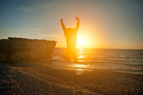 Free 골든 아워 동안 해변에서 점프하는 사람 Stock Photo