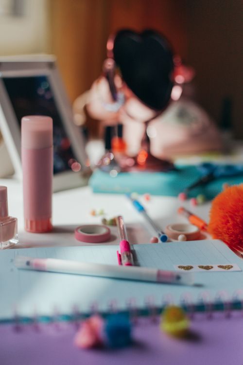 Free A vibrant, cluttered desk featuring colorful stationery and a heart-shaped mirror. Stock Photo