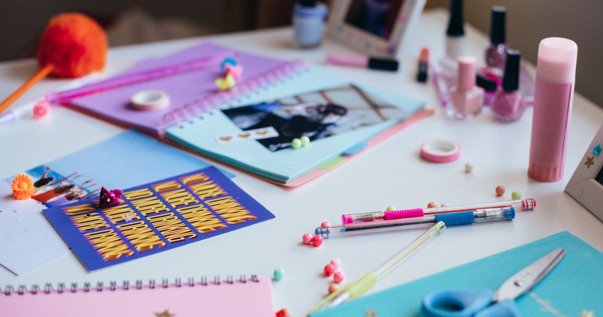 Craft supplies including scissors, colored paper, and string arranged on a wooden table in natural light