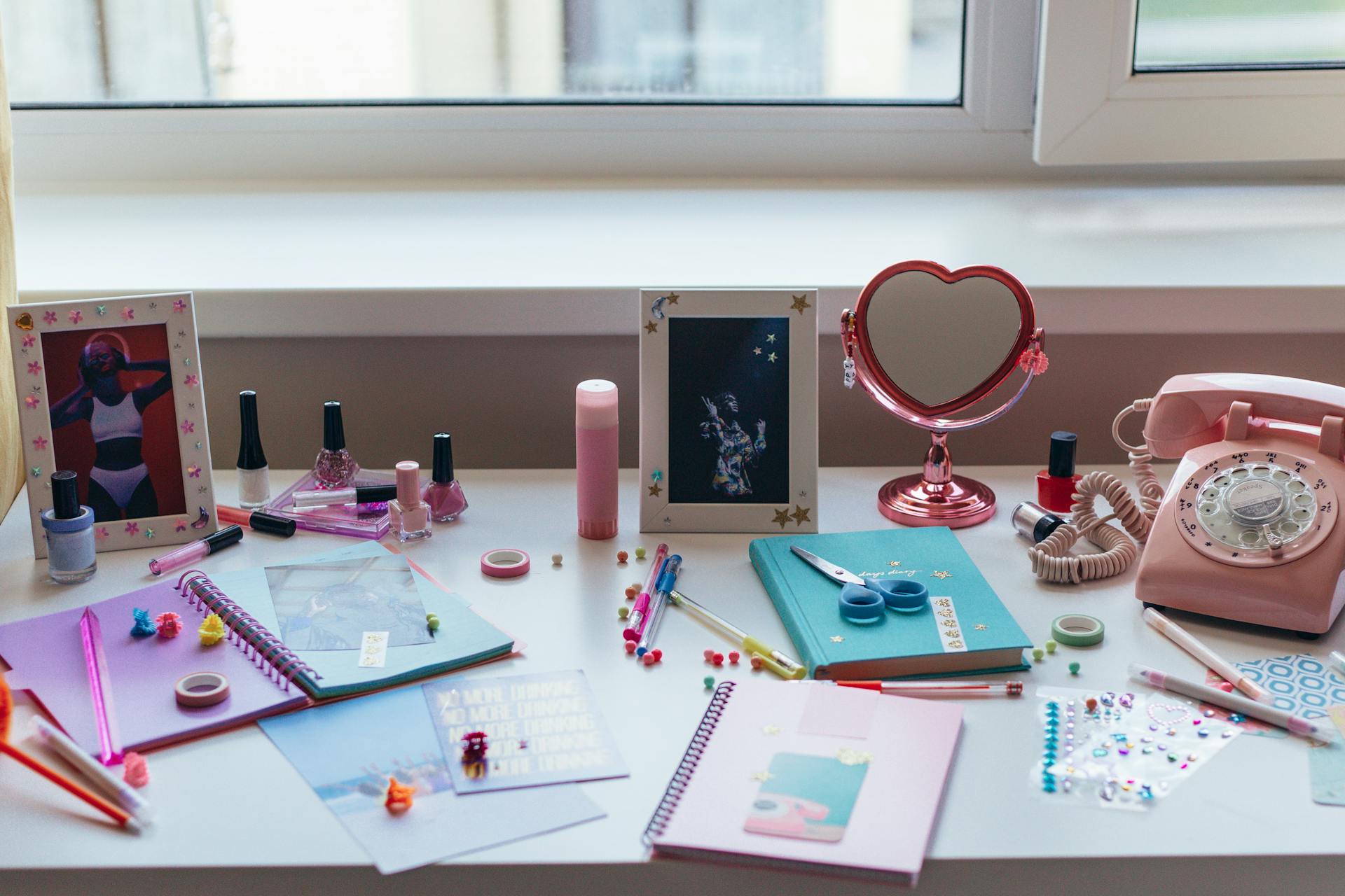 Notebooks and Pink Touchpad Telephone on White Desk