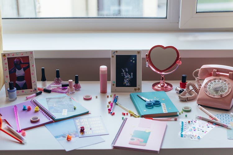 Notebooks And Pink Touchpad Telephone On White Desk 