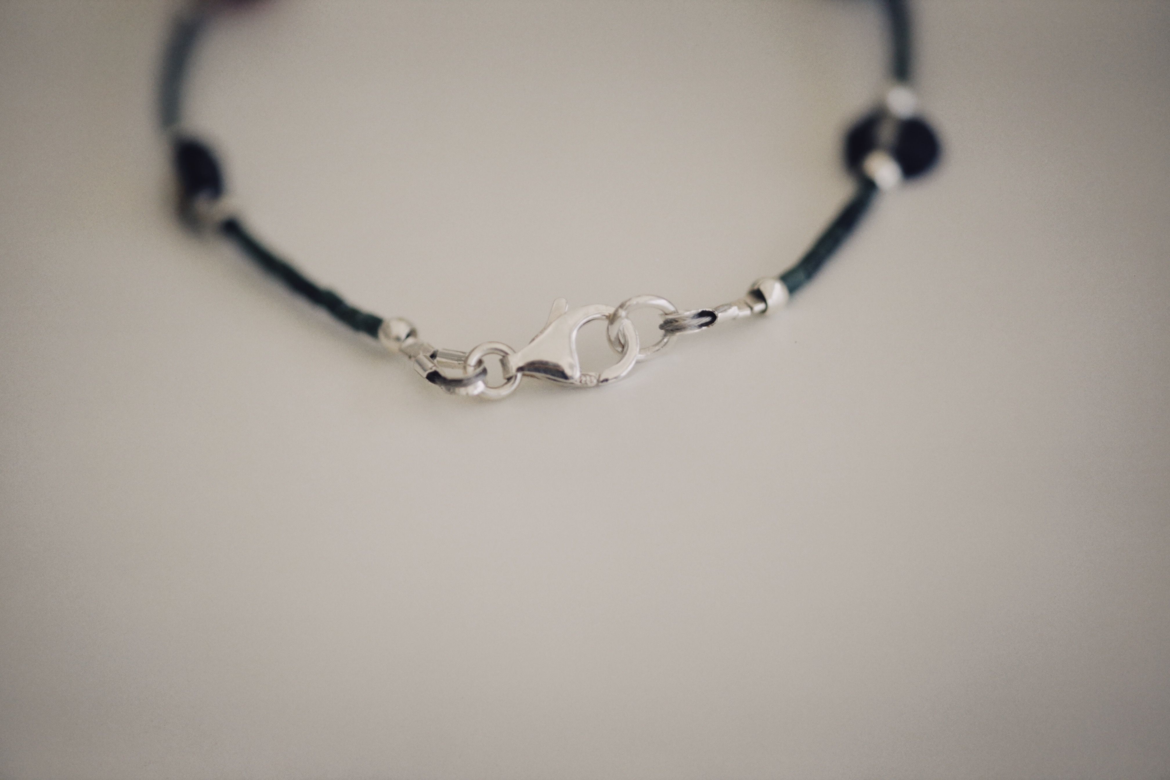 Gros plan sur un fermoir mousqueton fixé à un bracelet fin, illustrant les différents types de fermoirs de bracelets