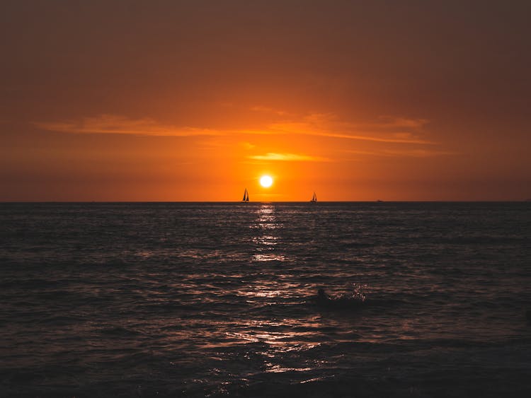 Sea At Sunset And Silhouette Of Ships In The Distance 