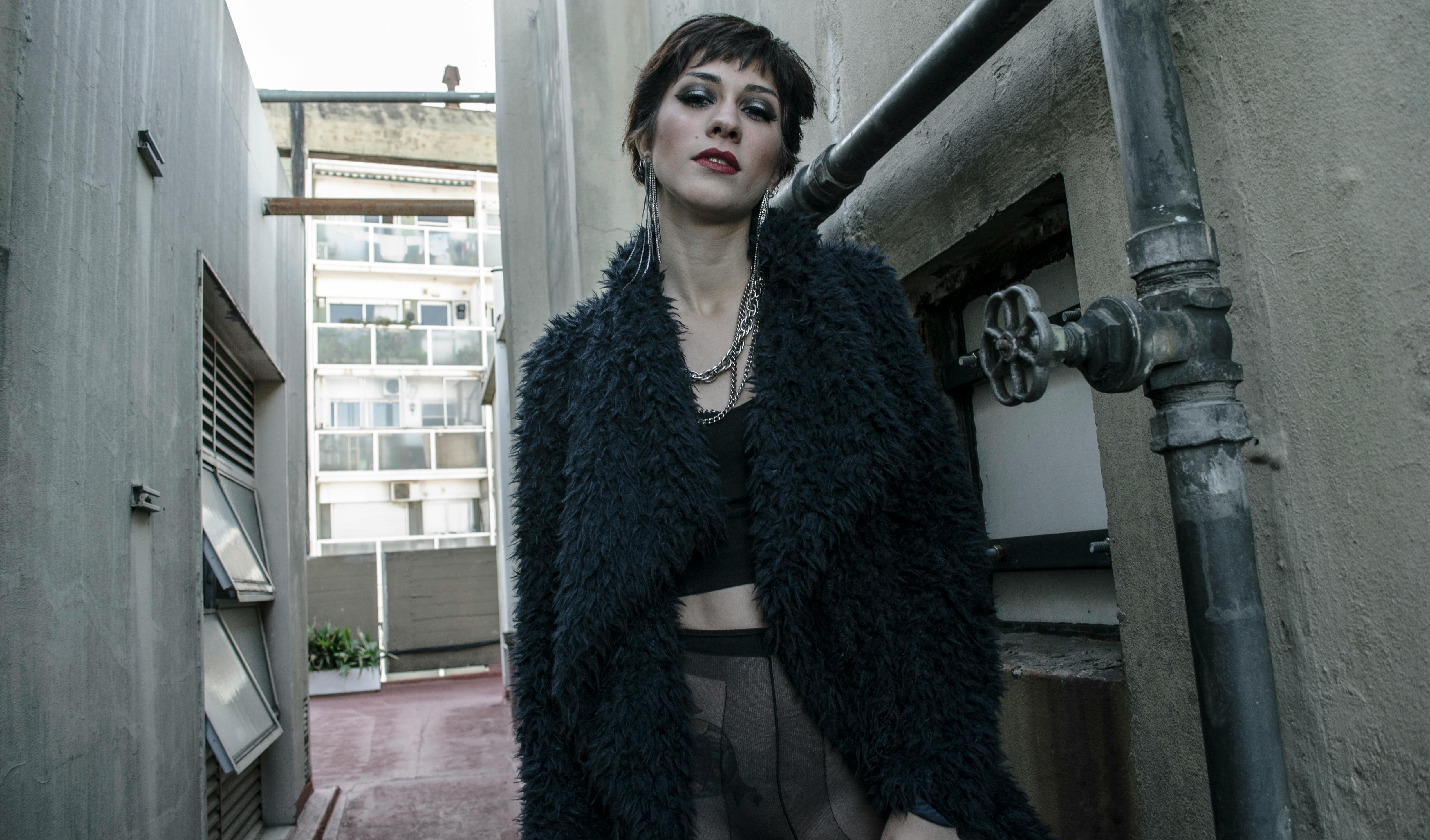 Stylish woman in fur coat posing in an urban alleyway.