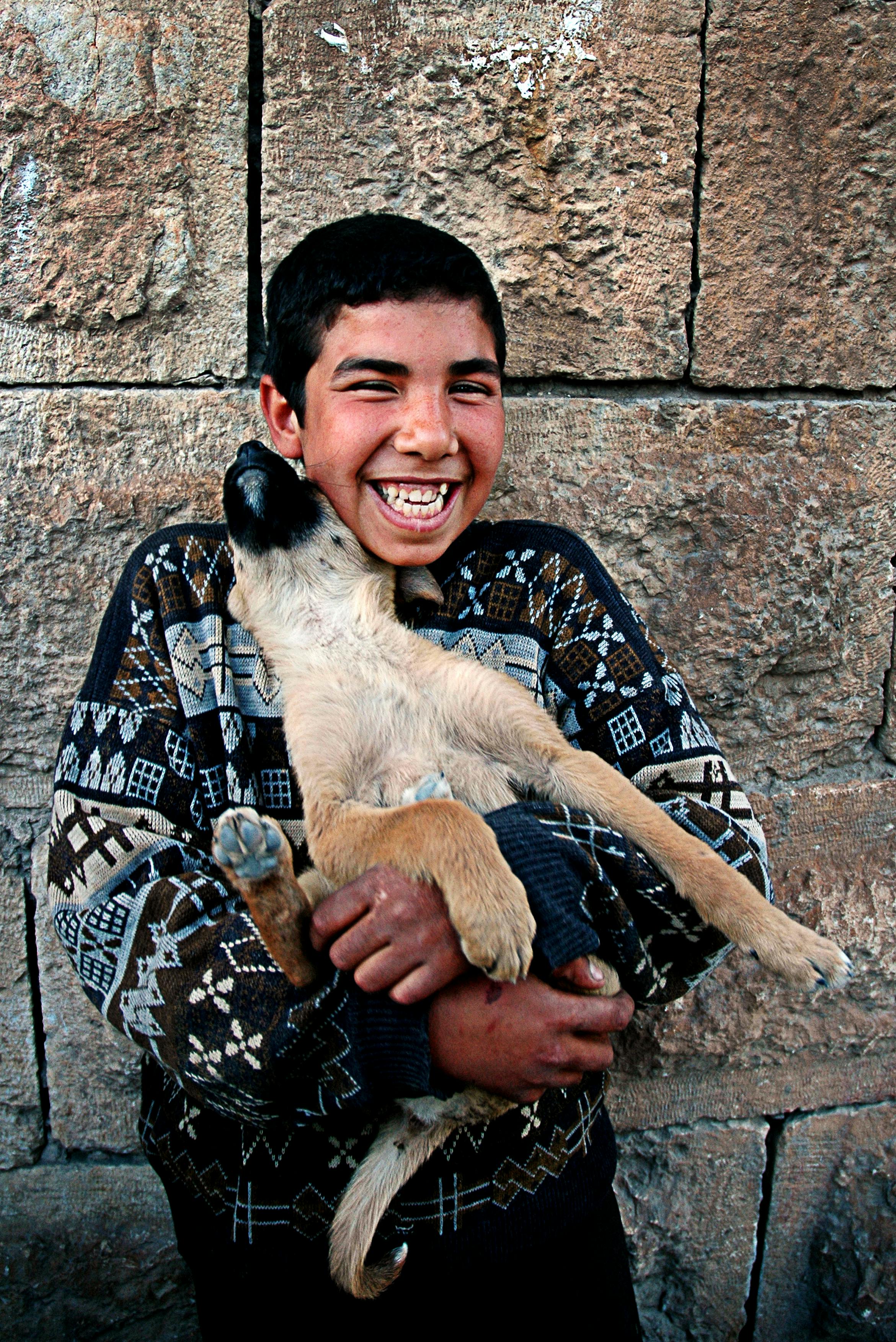 photo of a boy carrying his dog while smiling