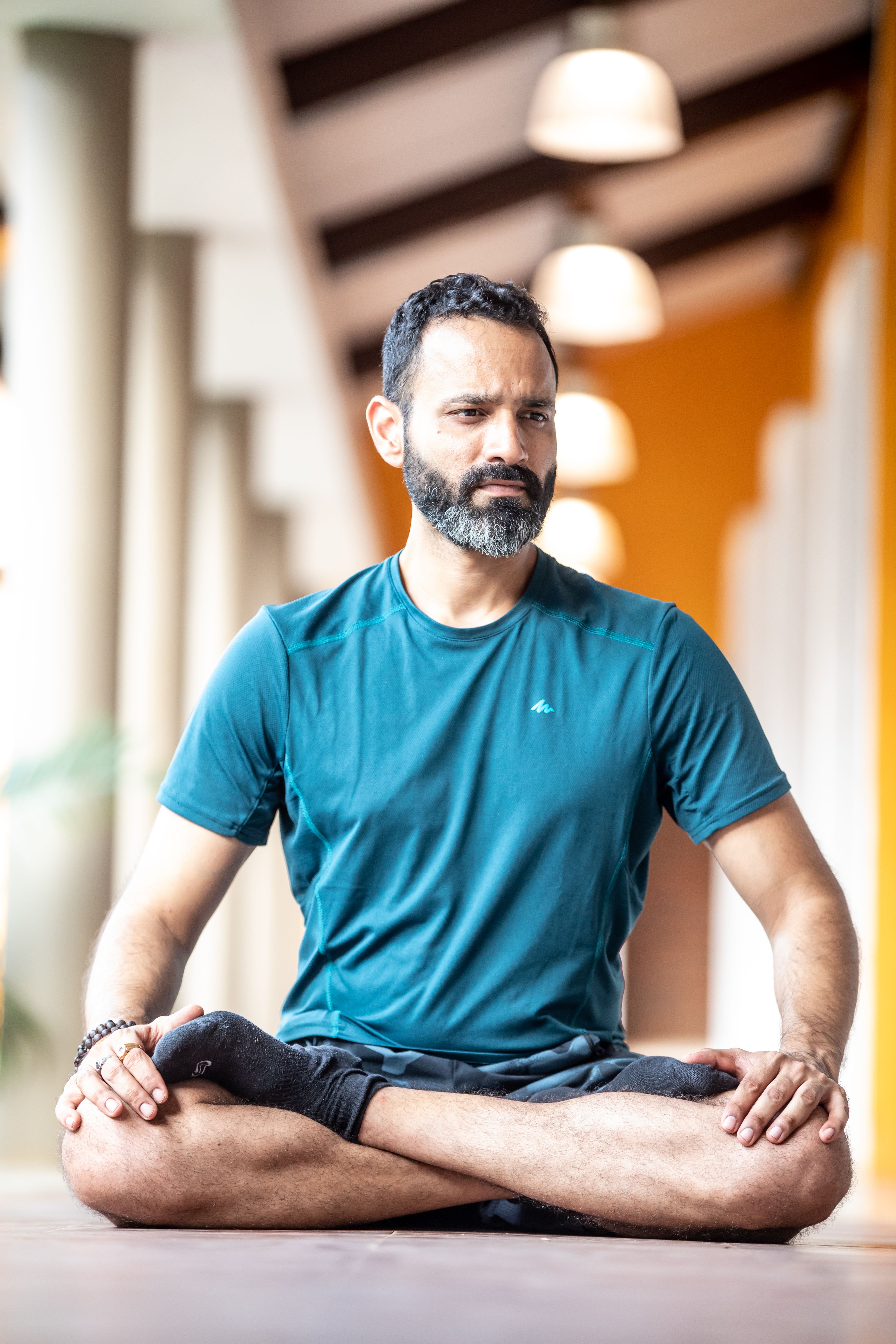 Adult male sitting in a meditative pose indoors, showcasing mindfulness and tranquility.