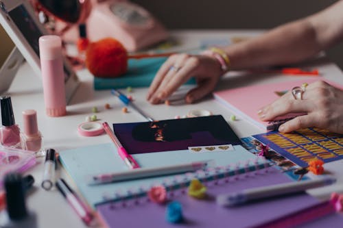 Free Woman Hands on Table with Colorful Notebooks and Pens Stock Photo