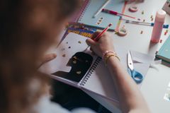 A student decorates a notebook with stickers and colorful supplies, engaging in a creative art project.