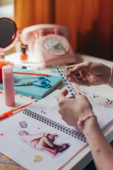 Hands decorating a scrapbook with colorful stickers and vintage items, capturing a DIY crafting theme.