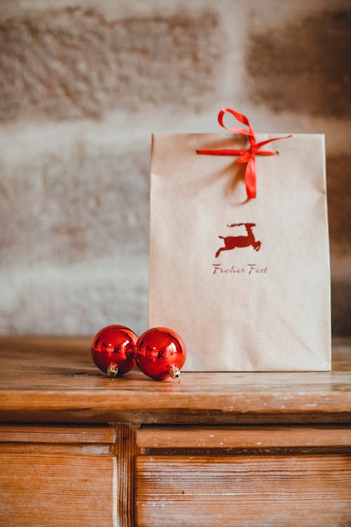 White Paper Bag With Red Baubles on Brown Wooden Table