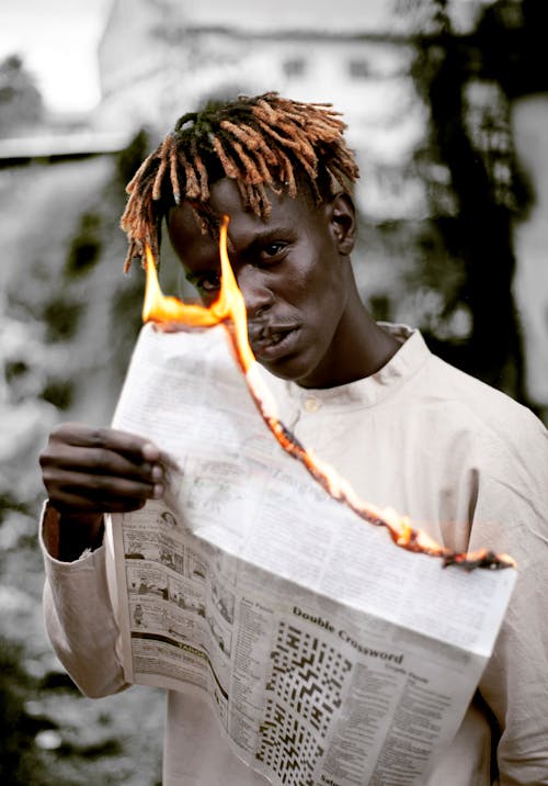 Free Man in White Long Sleeve Shirt Holding a Burning Newspaper Stock Photo