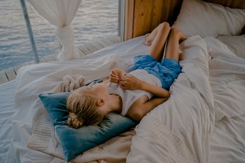 Free Young girl relaxing on a bed by the lake, enjoying a serene lakeside view. Stock Photo