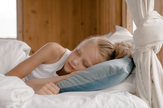 A young girl peacefully sleeping in a comfortable bed amidst soft pillows and blankets, evoking tranquility.