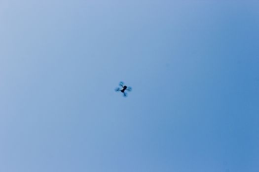 A high-angle view of a drone flying against a clear blue sky.
