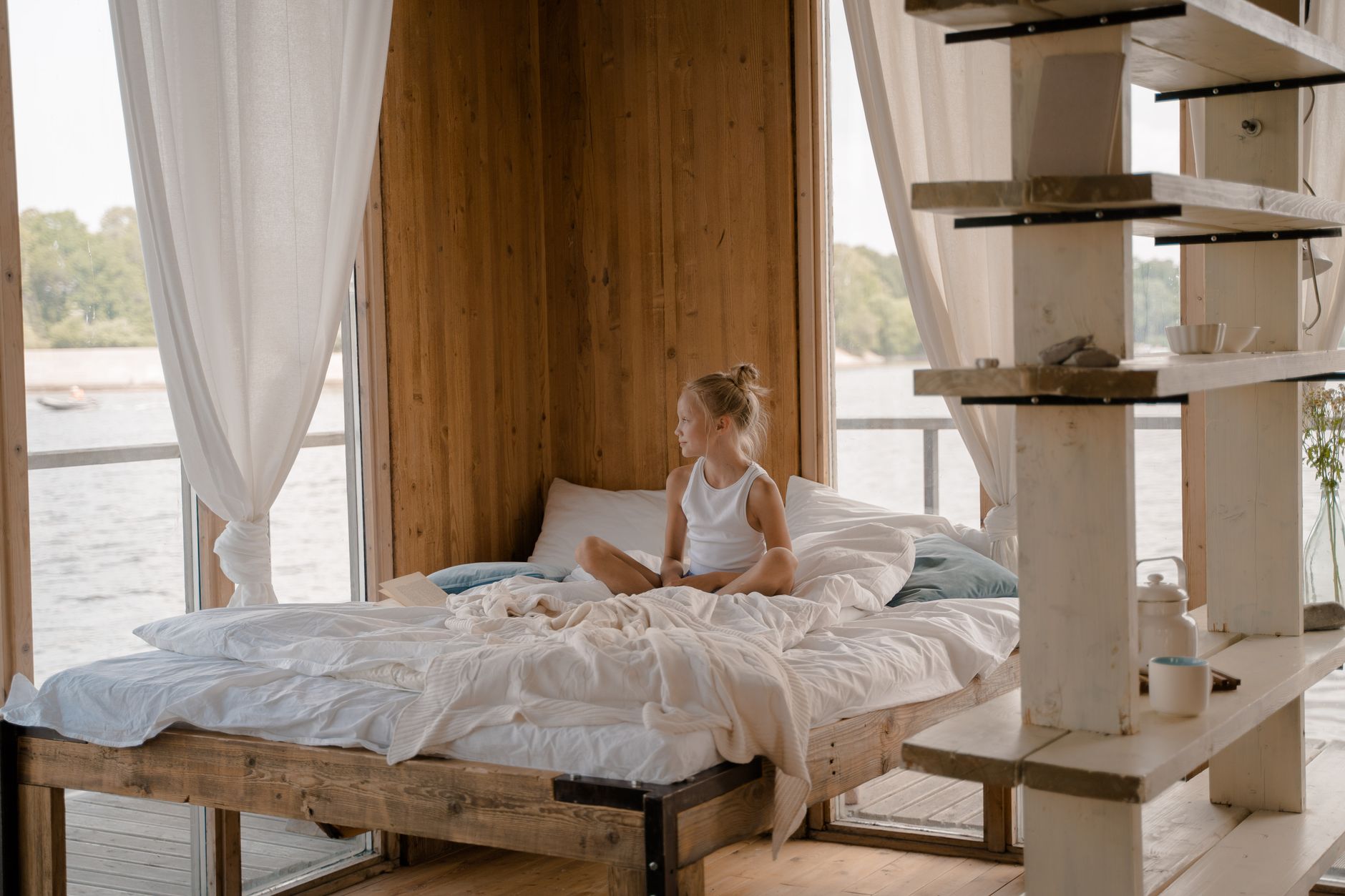 a cozy lakeside inn bedroom with crisp white linens and a window seat overlooking the water