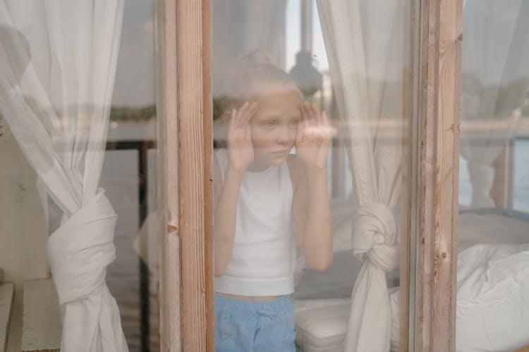 Sad Child Looking Through Window