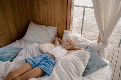 Free Child Lying on Bed with Hands behind Head Stock Photo