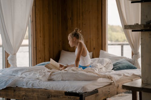 Child Reading Book in Bed