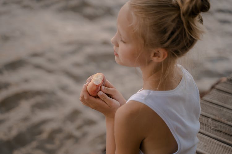 Girl Eating A Peach On A Pier 