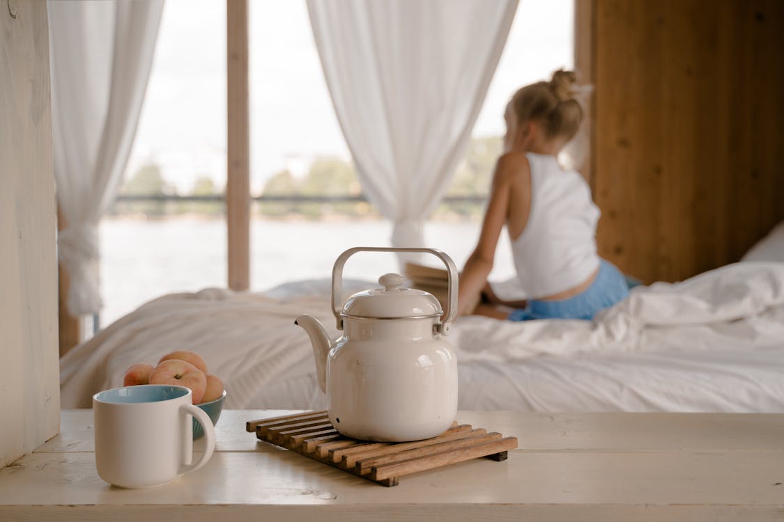 Free Young Girl Sitting on Bed with Breakfast on Table Stock Photo