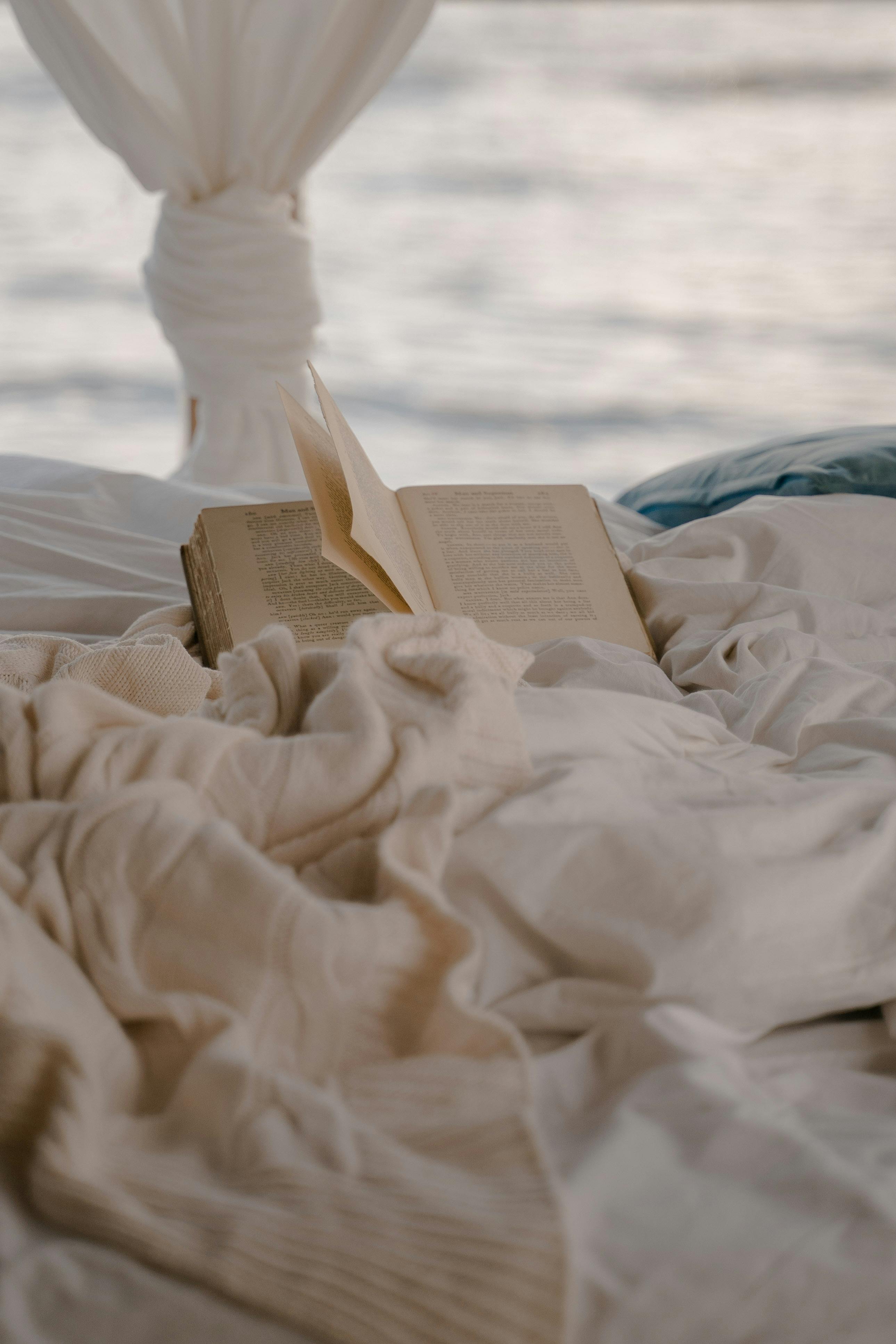 open book lying on bed with sea outside window