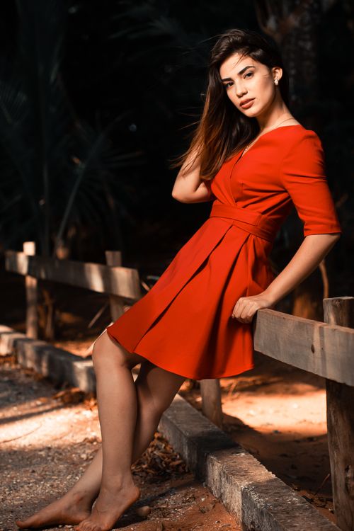 Free Stylish woman in a red dress poses gracefully outdoors, embracing natural beauty. Stock Photo