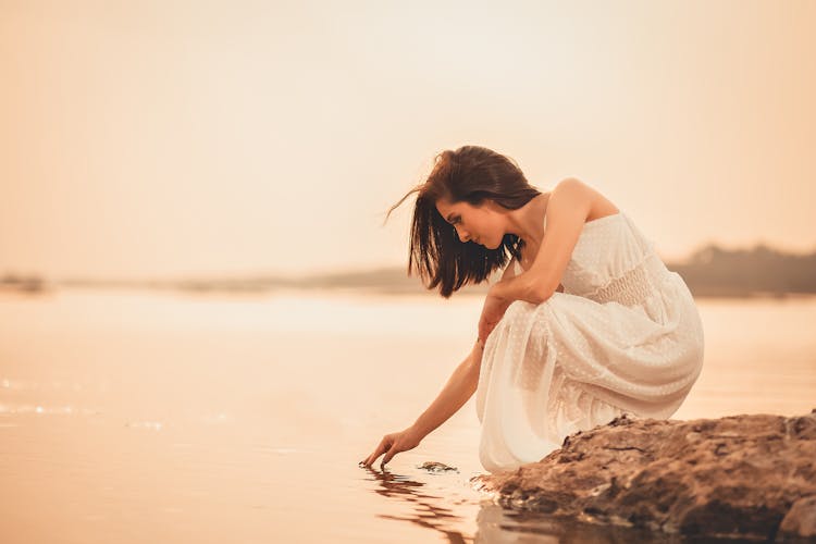 Woman In Dress Touching Water