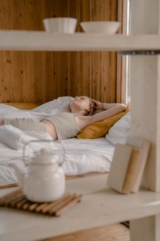 Woman lying in a serene wooden bedroom, embracing tranquility and relaxation.