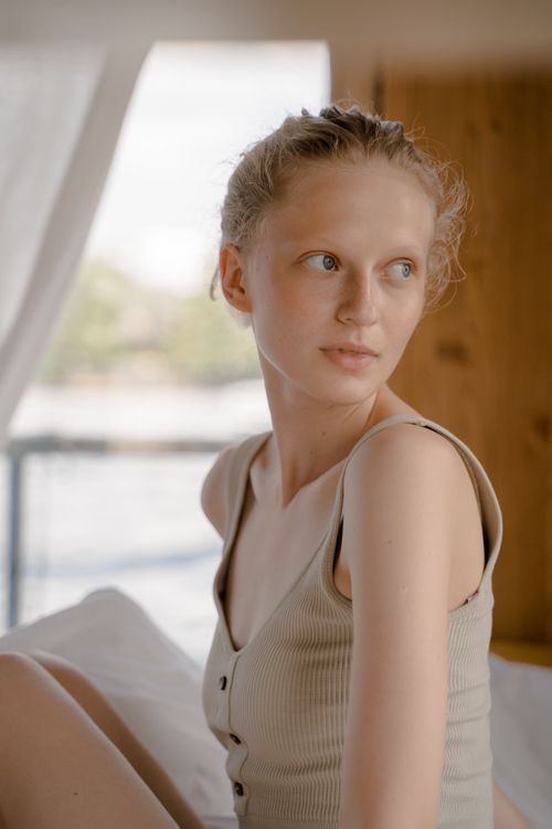 Free Portrait of a thoughtful woman sitting indoors, bathed in soft natural light. Stock Photo