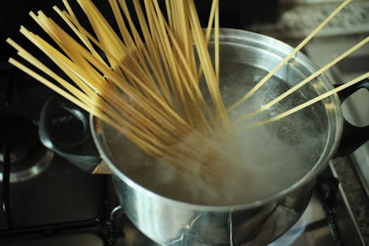 Uncooked spaghetti being cooked in a boiling pot of water, steam rising.