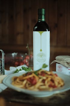 Close-up of Italian pasta and Calabria olive oil, showcasing a gourmet dinner setting.