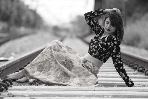 Monochrome Photo of a Woman Posing on a Railway Track