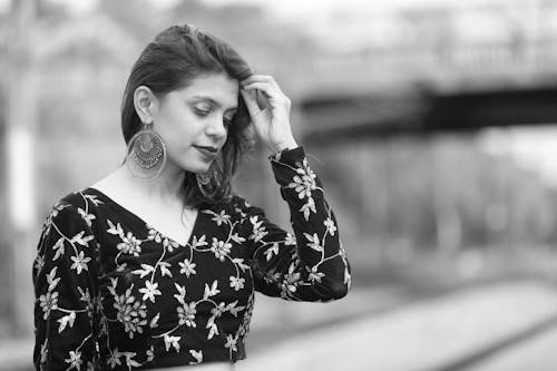Free Grayscale Photo of a Woman in a Floral Crop Top Fixing Her Hair Stock Photo