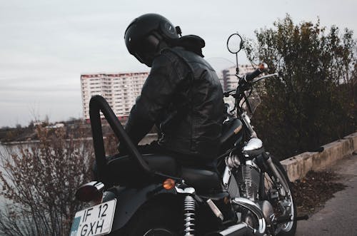 Photo of a Person in a Black Leather Jacket Sitting on a Parked Motorcycle