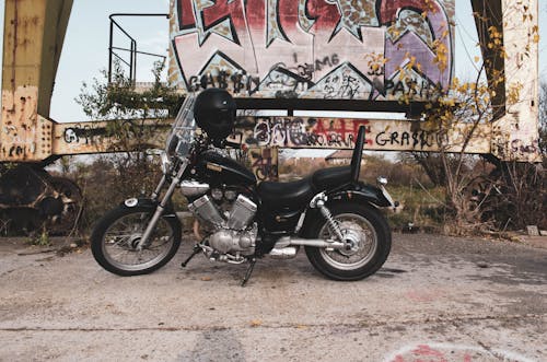 Photo of a Black Motorcycle Parked Near Graffiti Art
