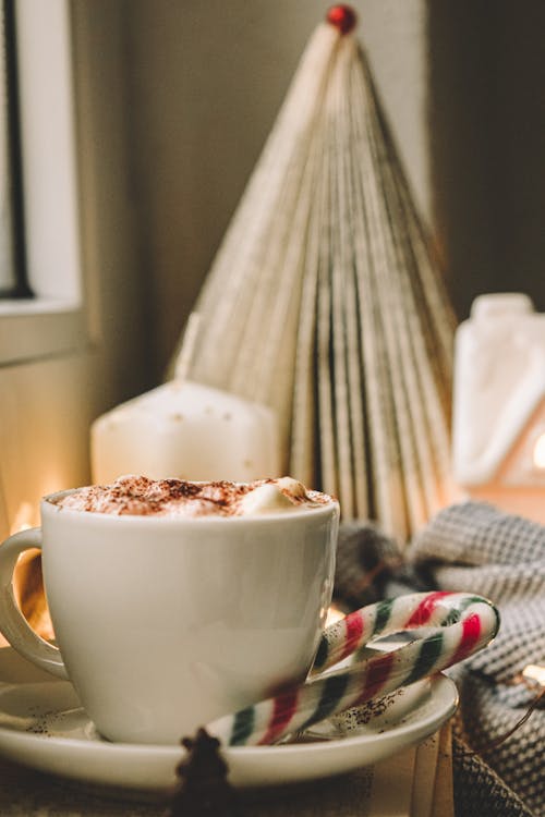 White Ceramic Mug With Coffee Beside a Candy Cane