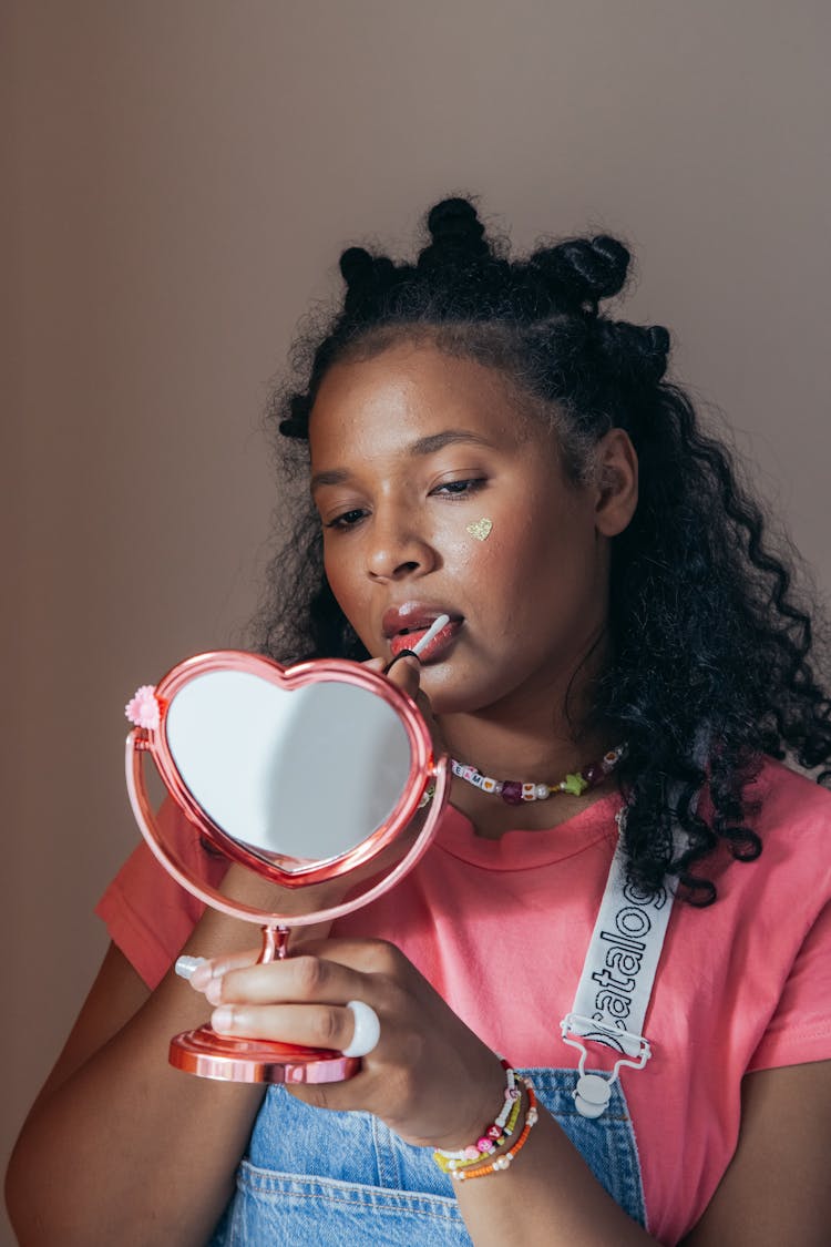 Woman Holding Mirror While Putting Makeup