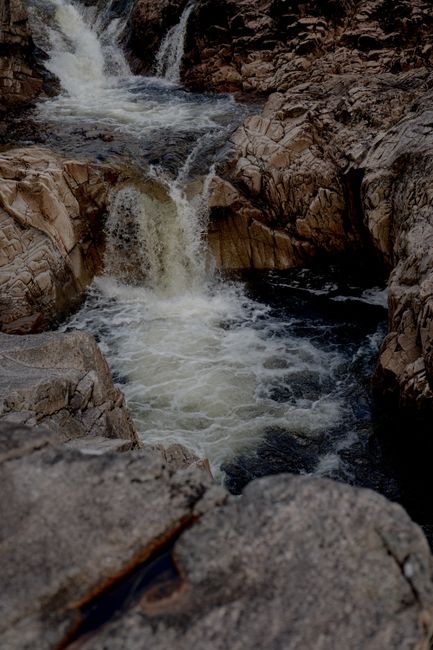 A serene waterfall cascading through jagged rocks, showcasing nature's beauty in a rugged landscape.