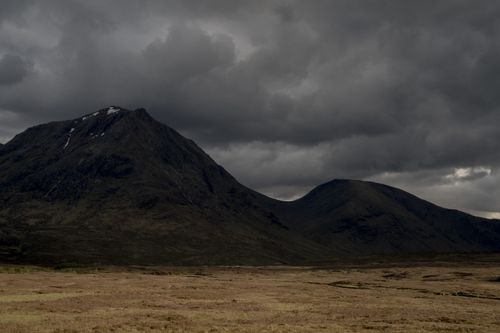 Free A dramatic mountain landscape captured under dark, stormy skies suggesting impending weather change. Stock Photo
