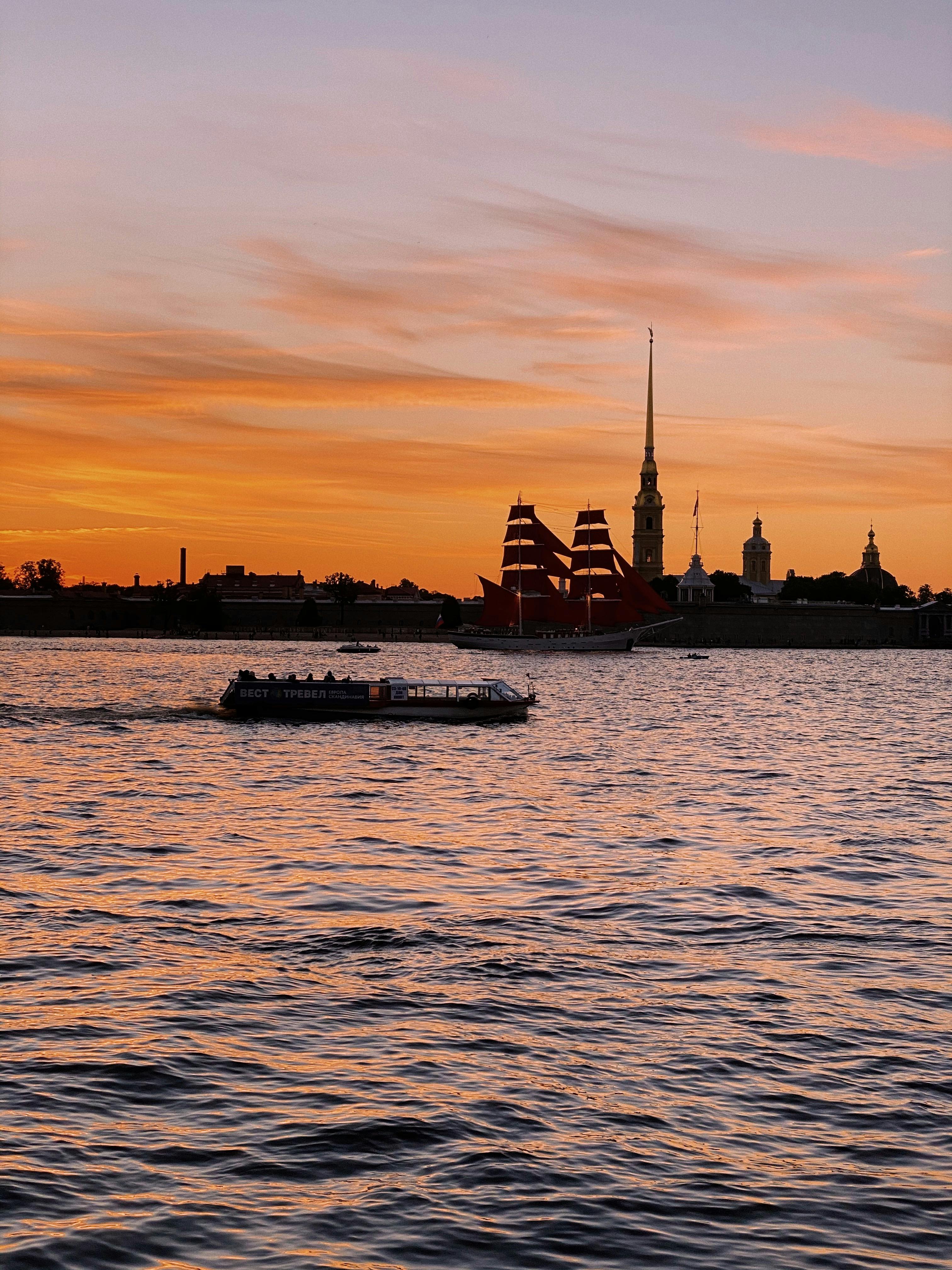 A serene sunset view with boats on Neva River in Sankt-Peterburg, Russia.