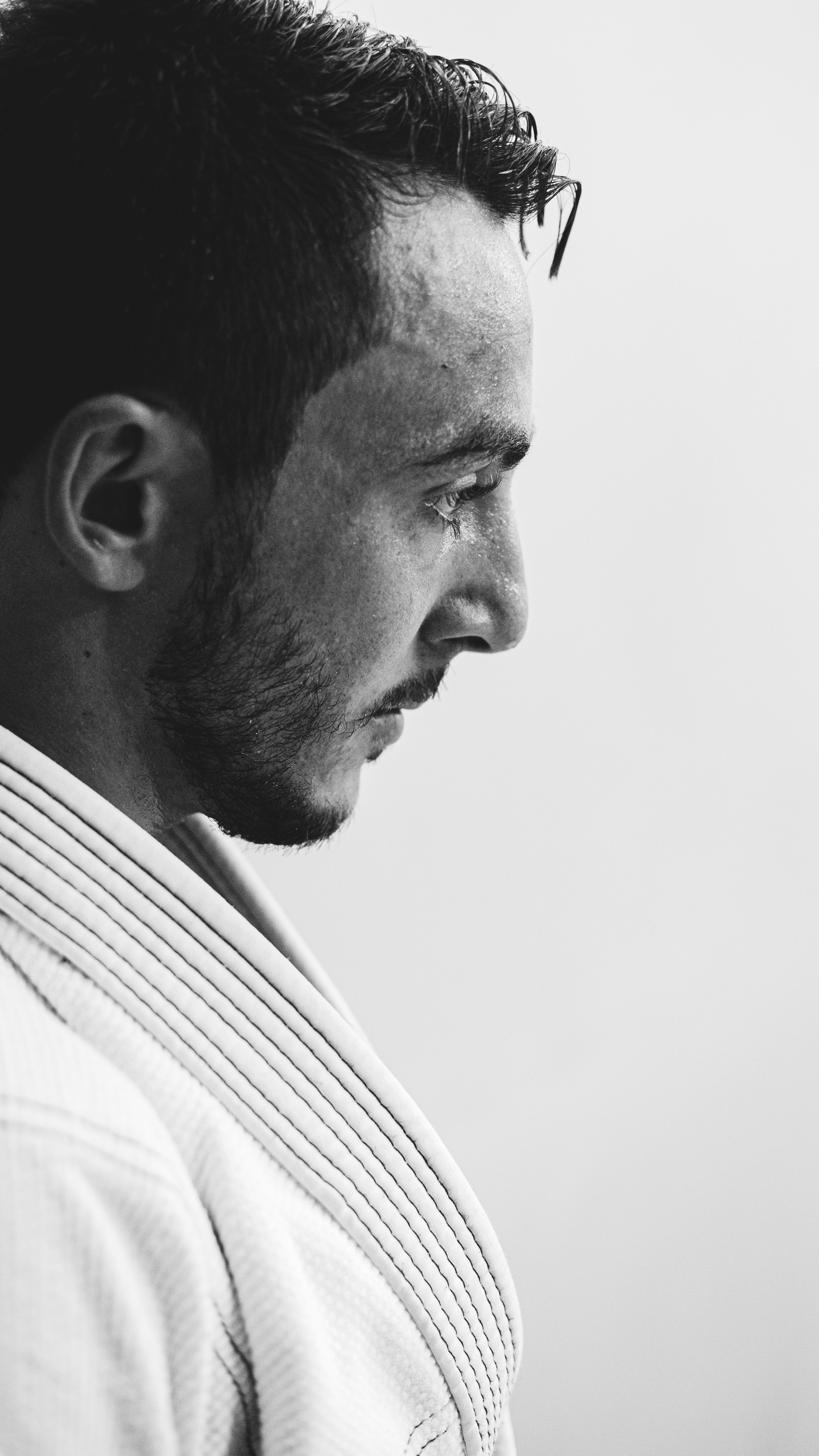 Profile portrait of a man wearing a kimono captured in black and white, showcasing focus and determination.