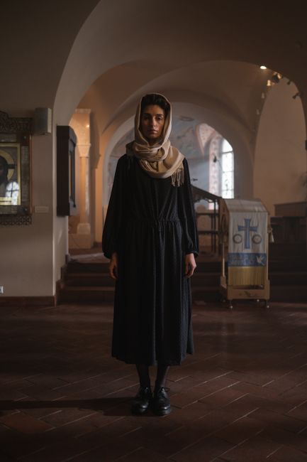 A serene woman stands in a beautifully lit church interior, symbolizing tranquility and faith.
