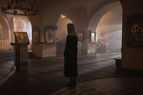 Free A contemplative scene inside a church with a woman standing among religious icons. Stock Photo