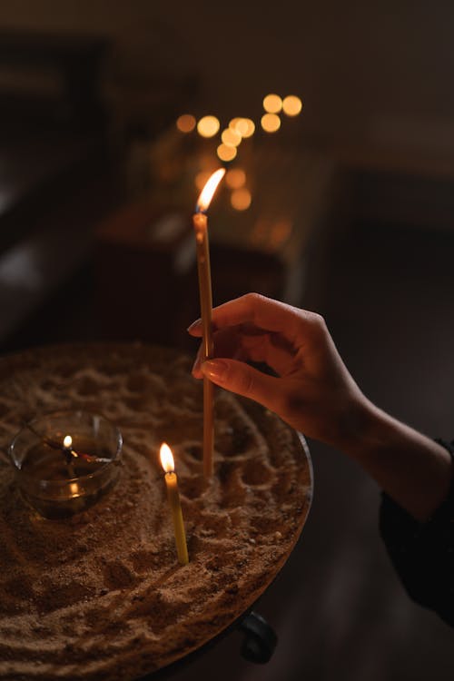 Person Placing a Lighted Candle on Sand