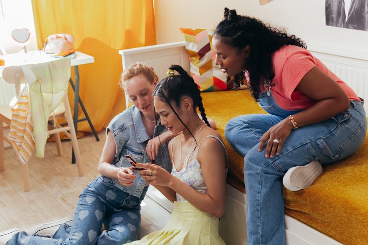 Teenagers In A Bedroom Using A Mobile Phone