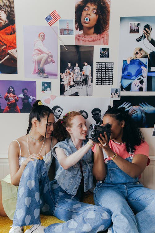 Friends with Video Camera against Wall with Posters