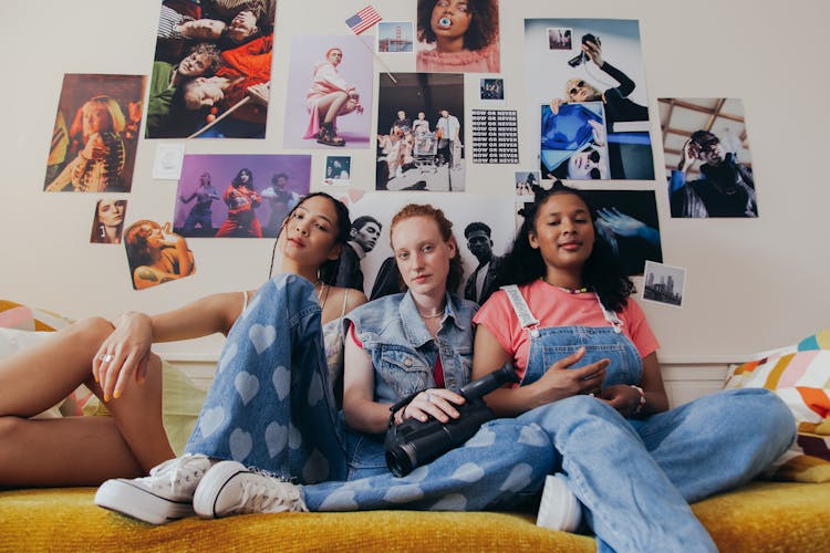 Women Sitting Leaning On The Wall With Posters 